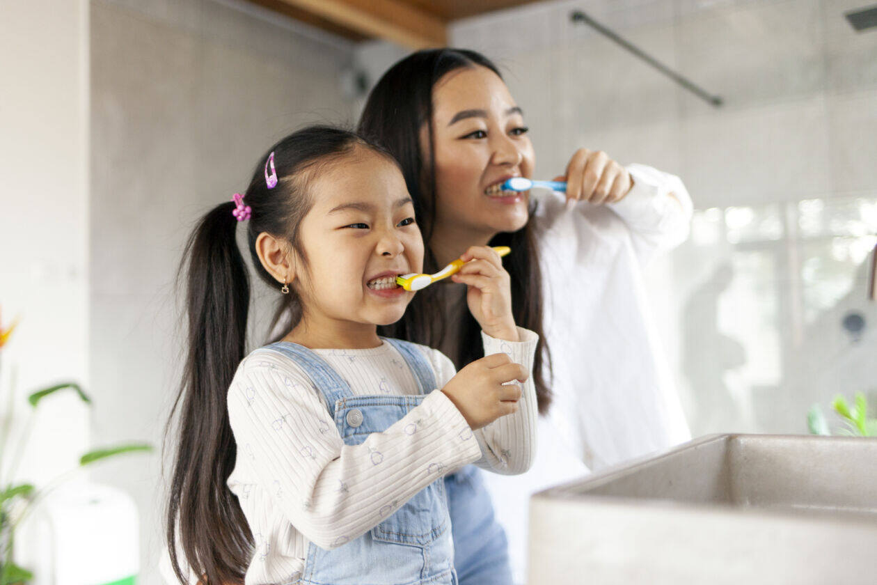 asian little girl with mom brushing teeth in bathroom, korean woman helping to brush daughter’s teeth at home together Cosmeticdentistwesthollywood