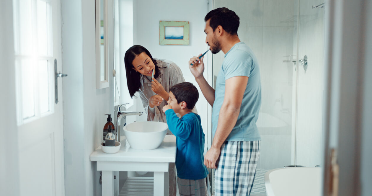 Parents, child and brushing teeth in family home bathroom while learning or teaching dental hygiene. A woman, man and kid with toothbrush and toothpaste for health, cleaning mouth and wellness dentistcosmeticwesthollywood